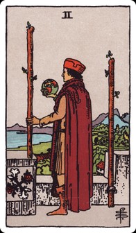 Two of Wands tarot card: a man on a castle battlement holds a small globe and looks out to sea.